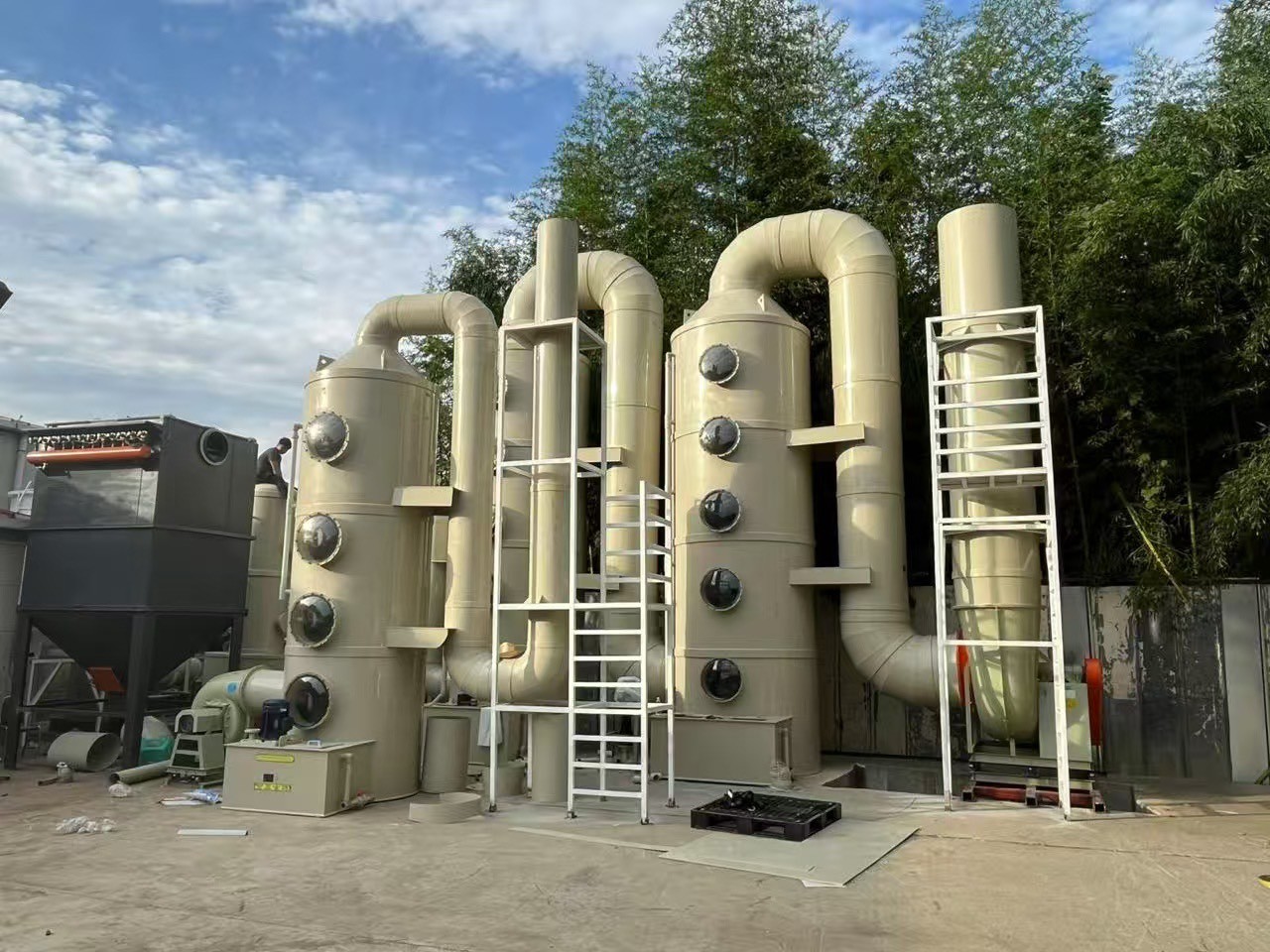 竹林を背景に屋外に設置された、複数ののぞき窓と複雑な配管を持つ大規模な産業用ガス洗浄装置(スクラバー)。