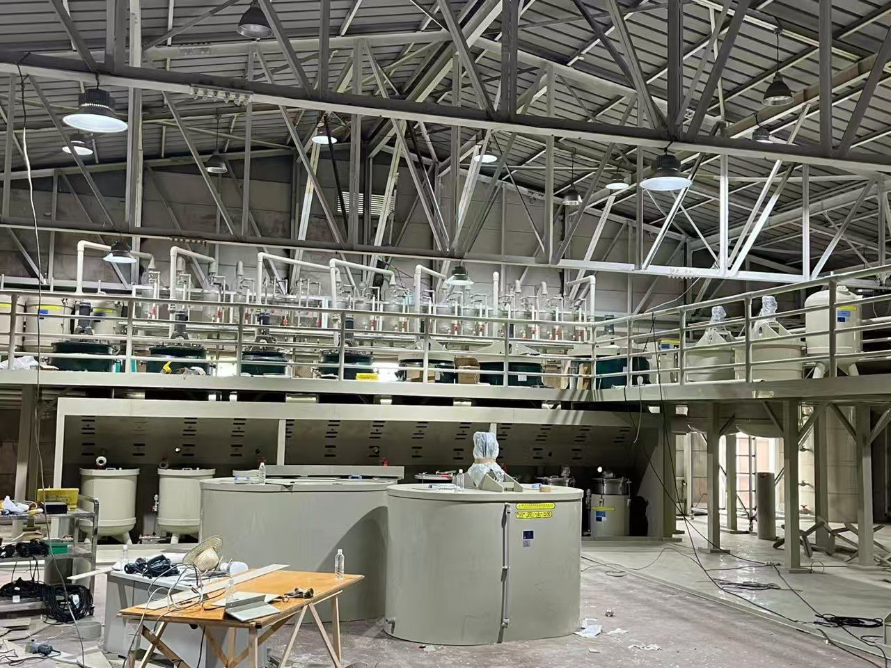 大型の貯蔵タンクや配管、高所の作業用足場が設置された工場の内部の様子。